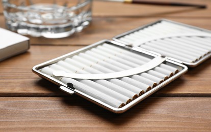 Photo of Stylish case with cigarettes on wooden table, closeup