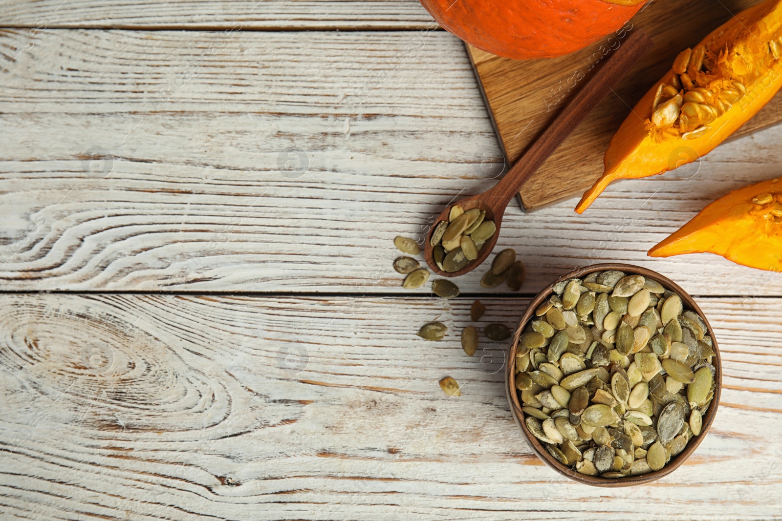 Photo of Flat lay composition with raw pumpkin seeds on white wooden table, space for text