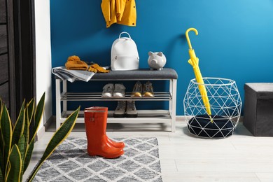 Photo of Stylish hallway with shoe storage bench near blue wall. Interior design