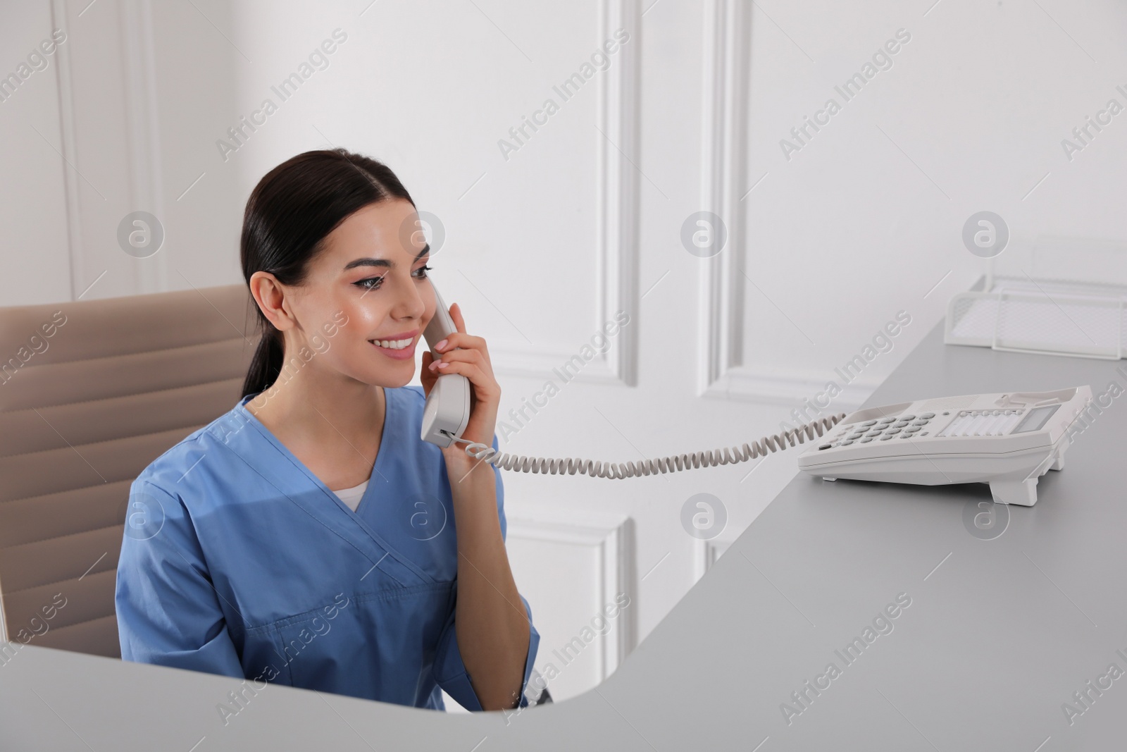 Photo of Receptionist talking on phone at countertop in hospital