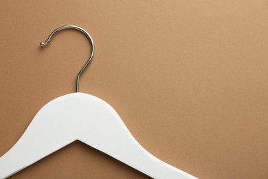 Photo of Empty white hanger on brown background, top view. Space for text