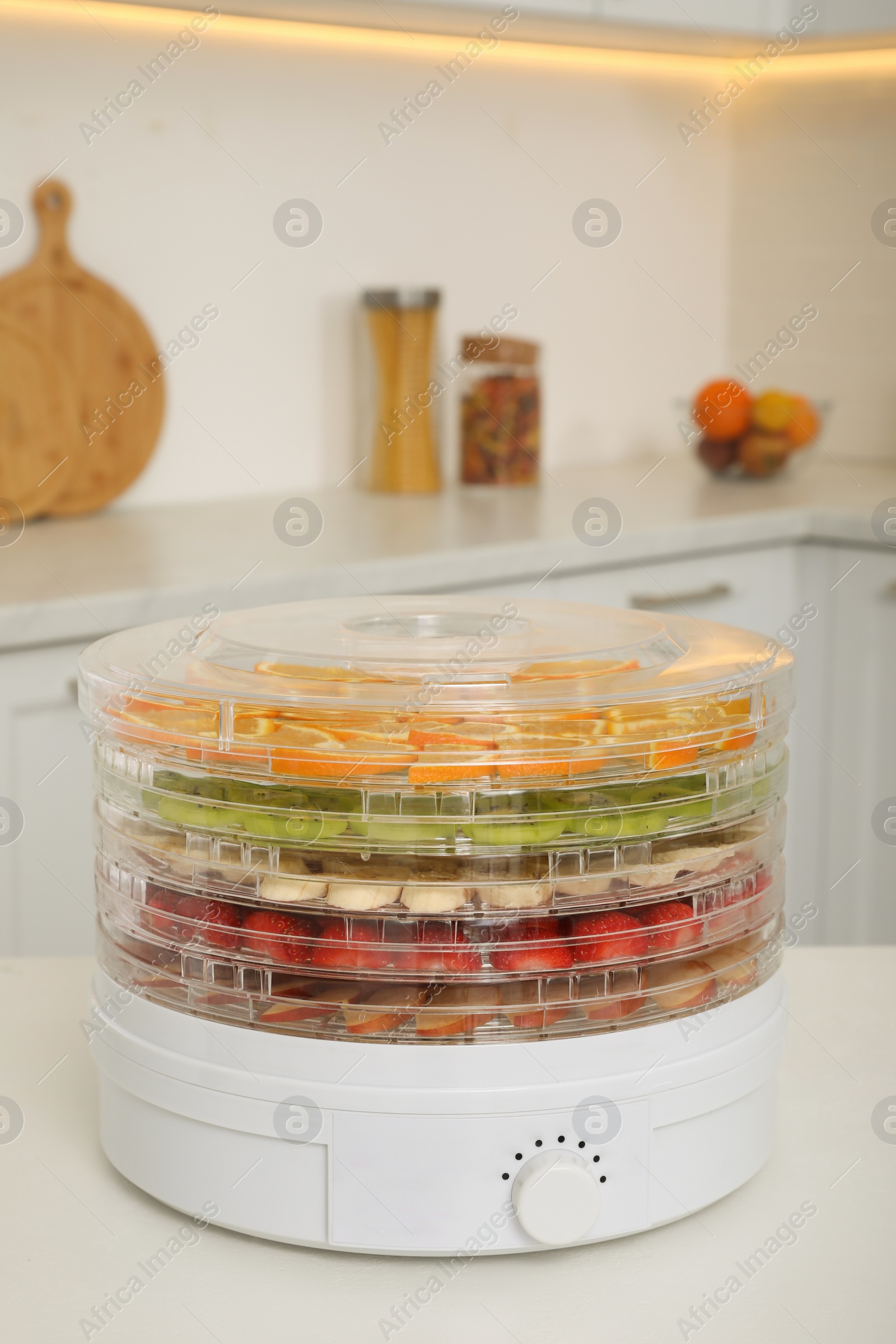 Photo of Dehydrator machine with different fruits and berries on white table in kitchen