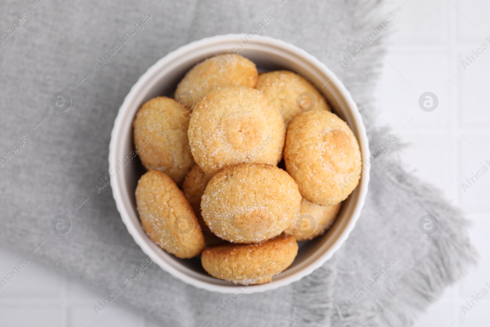 Photo of Tasty sugar cookies in bowl on white tiled table, top view