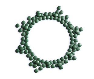 Photo of Frame of green spirulina pills on white background, top view with space for text