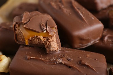 Photo of Many tasty chocolate bars with caramel as background, closeup