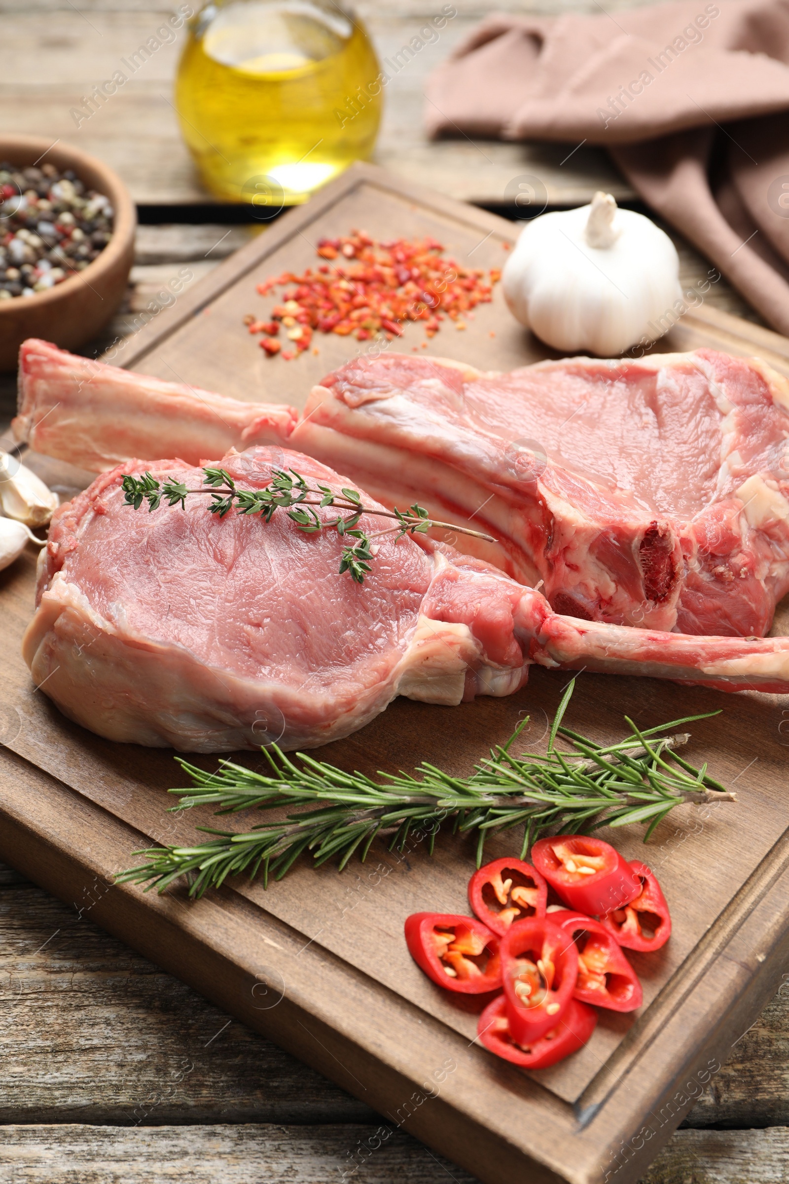 Photo of Fresh tomahawk beef cuts and spices on wooden table