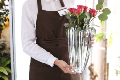 Female florist holding vase with bouquet in shop