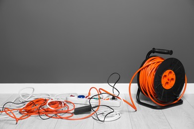 Photo of Extension cord reel plugged into power strip indoors, space for text. Electrician's equipment