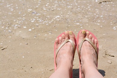 Woman wearing stylish pink flip flops on sandy beach, closeup. Space for text