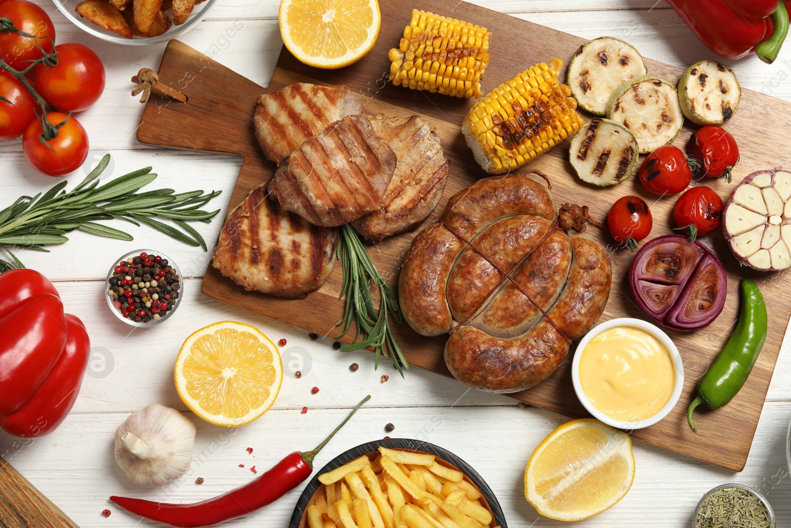 Photo of Barbecued meat and vegetables on white wooden table, flat lay