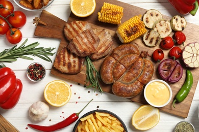 Barbecued meat and vegetables on white wooden table, flat lay