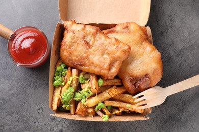 Photo of Tasty fish, chips, sauce and peas in paper box on grey table, top view