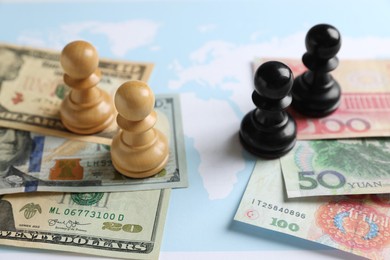 Photo of Chess pieces, yuan and dollar banknotes on world map. Trade war concept