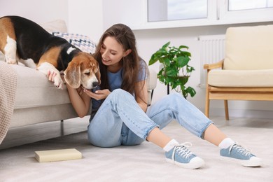 Photo of Happy young woman with her cute Beagle dog at home. Lovely pet