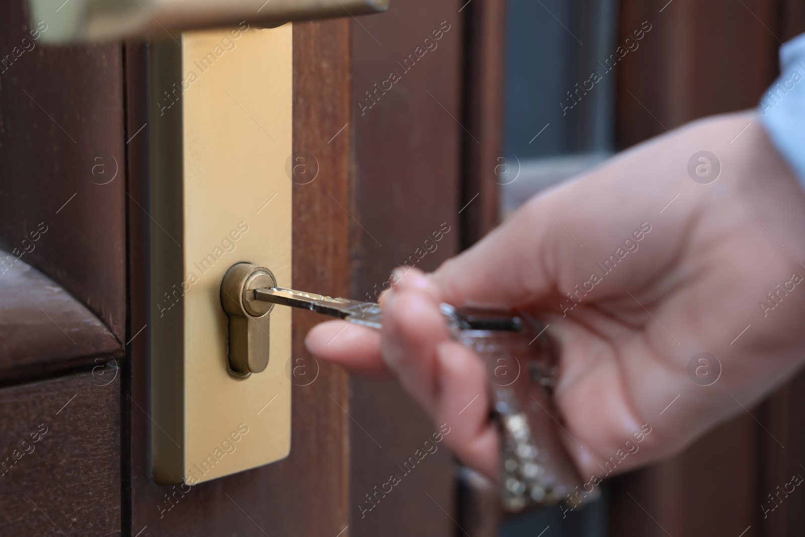 Photo of Woman opening door with key outdoors, closeup