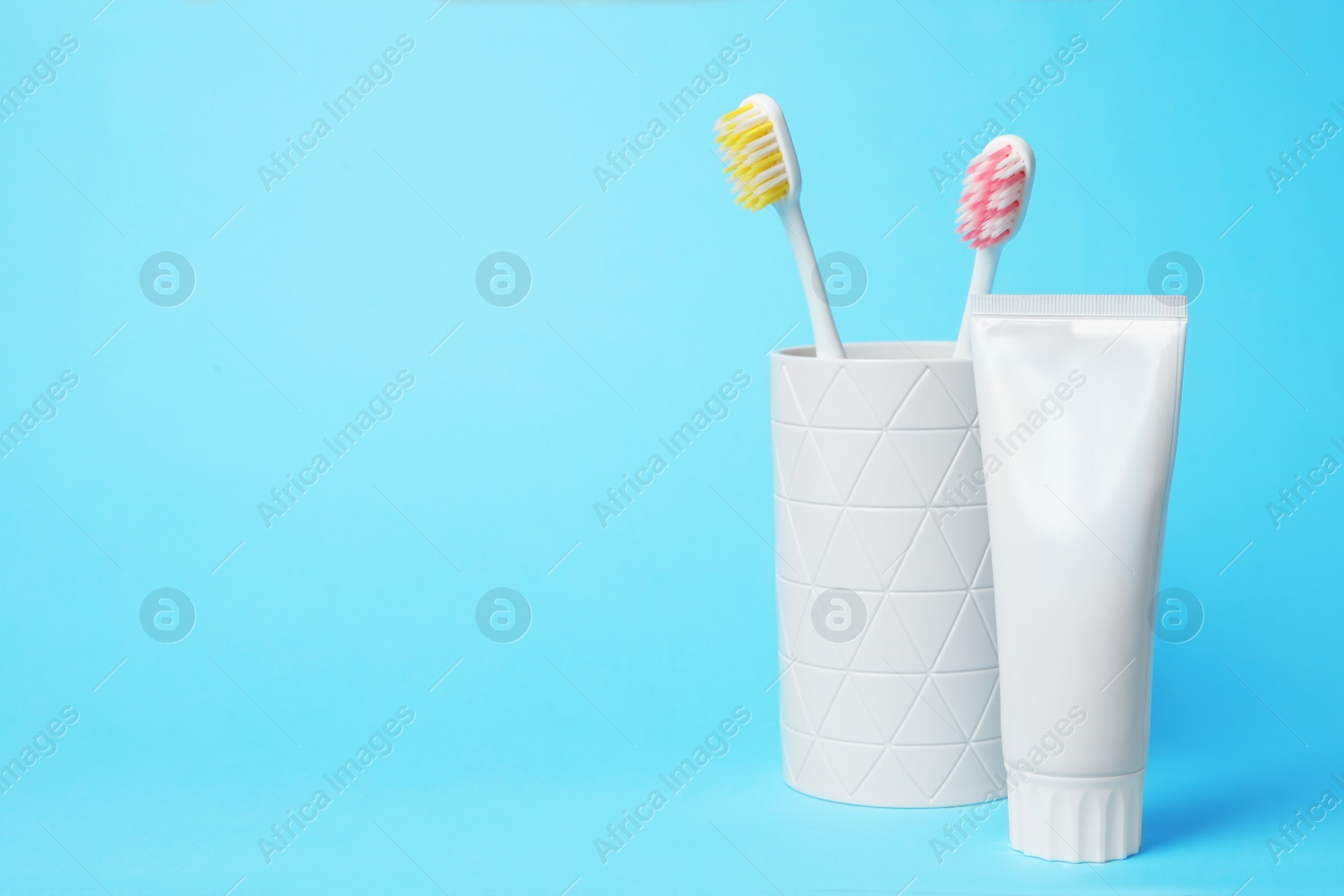 Photo of Holder with brushes and toothpaste on color background. Space for text