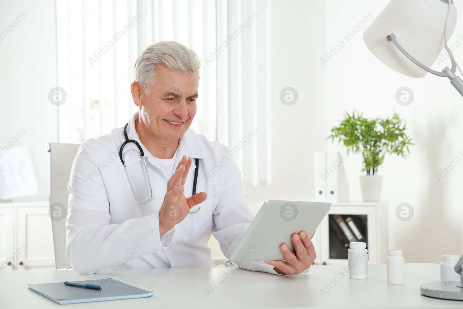 Photo of Doctor consulting patient using video chat on tablet in clinic