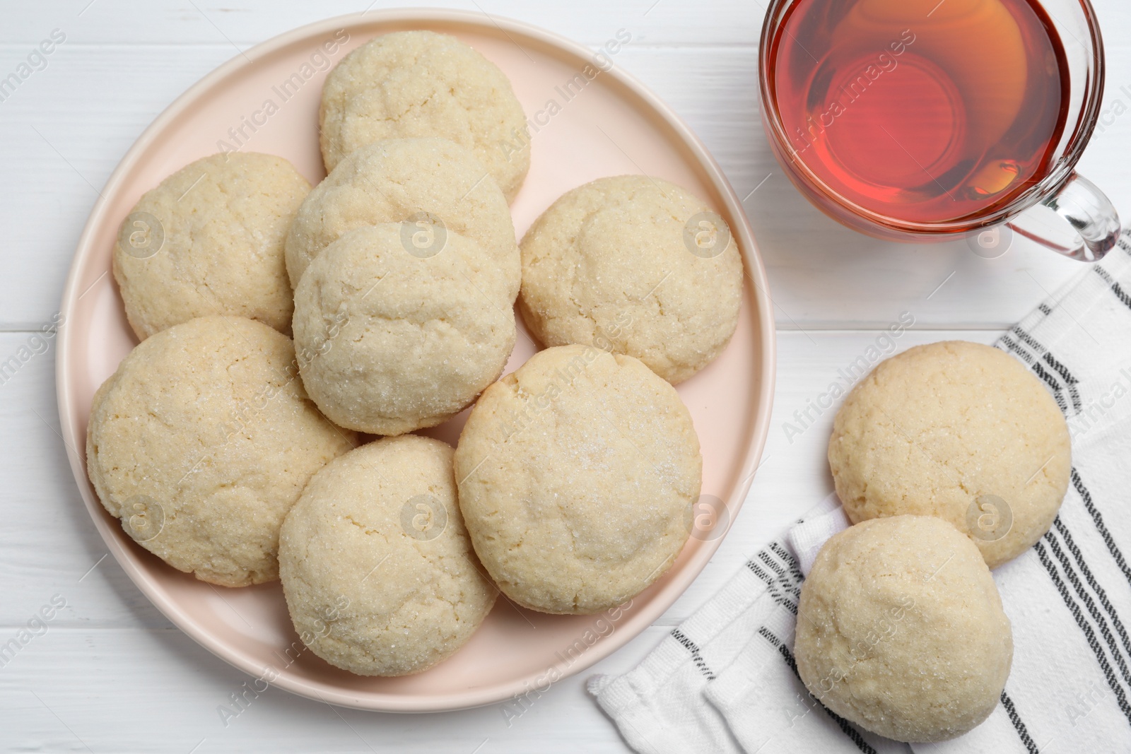 Photo of Delicious sugar cookies and cup of tea on white wooden table, flat lay