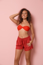 Beautiful African-American woman in beachwear on color background