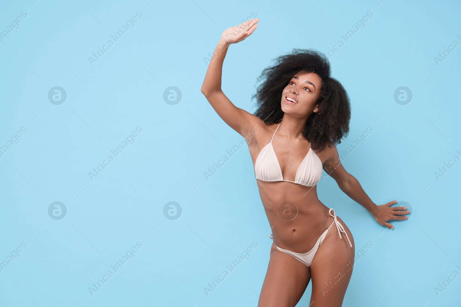 Photo of Beautiful woman in stylish bikini posing on light blue background, space for text