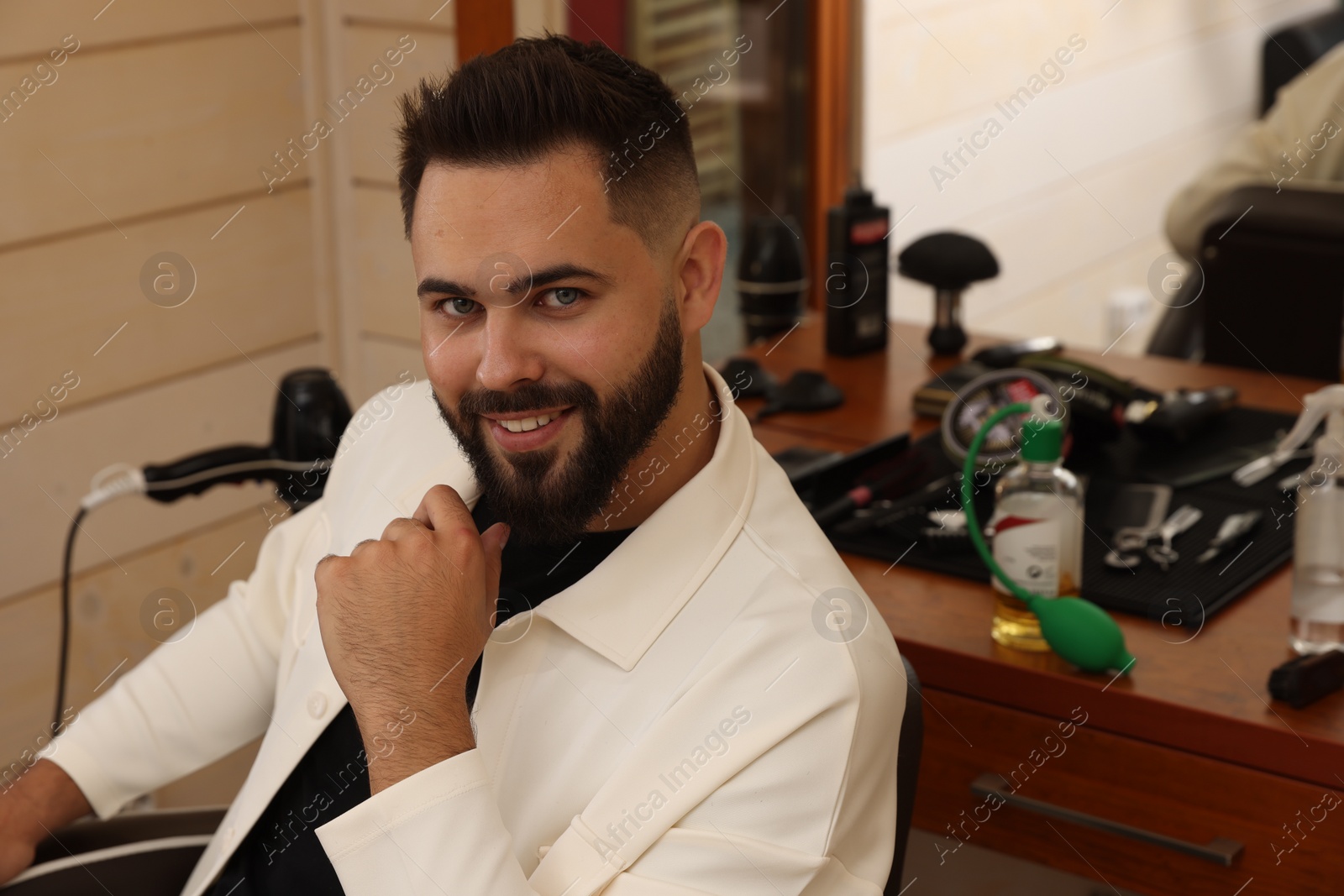 Photo of Young man with fresh haircut and groomed beard in barbershop