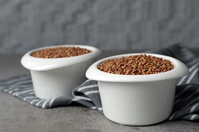 Photo of Uncooked buckwheat in bowls on table. Space for text