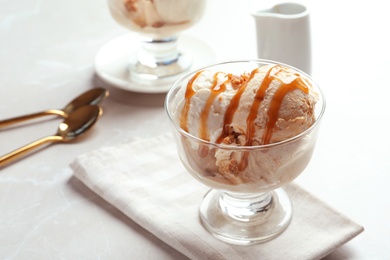 Photo of Bowl with caramel ice cream on table