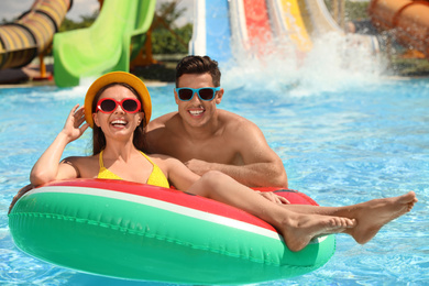 Happy couple with inflatable ring at water park. Summer vacation