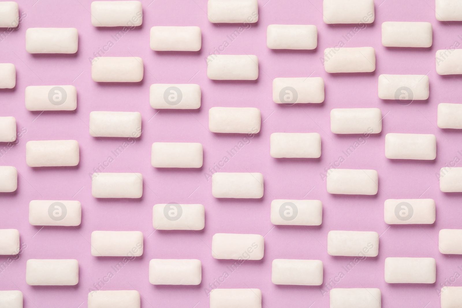 Photo of Many chewing gum pieces on pink background, flat lay