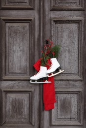 Pair of ice skates with Christmas decor hanging on old wooden door