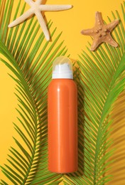 Sunscreen, sea stars and tropical leaves on yellow background, flat lay. Sun protection care