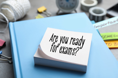 Reminder note with phrase ARE YOU READY FOR EXAMS and stationery on table, closeup