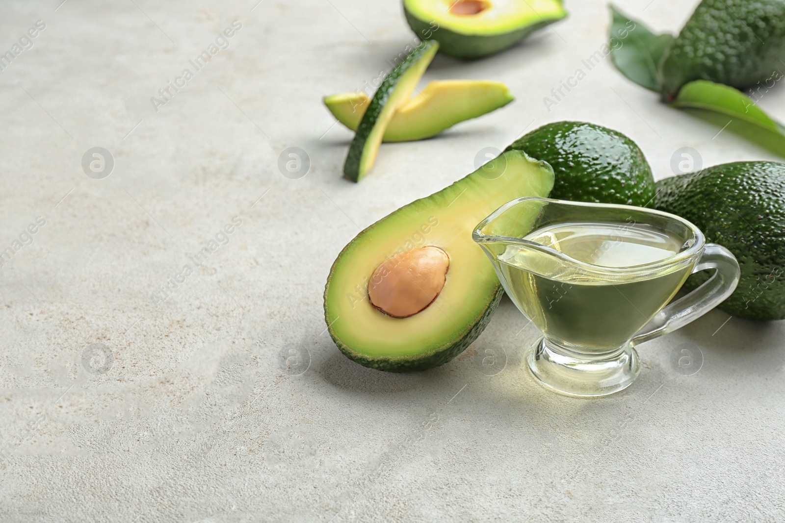 Photo of Composition with natural oil and avocados on grey stone background. Space for text