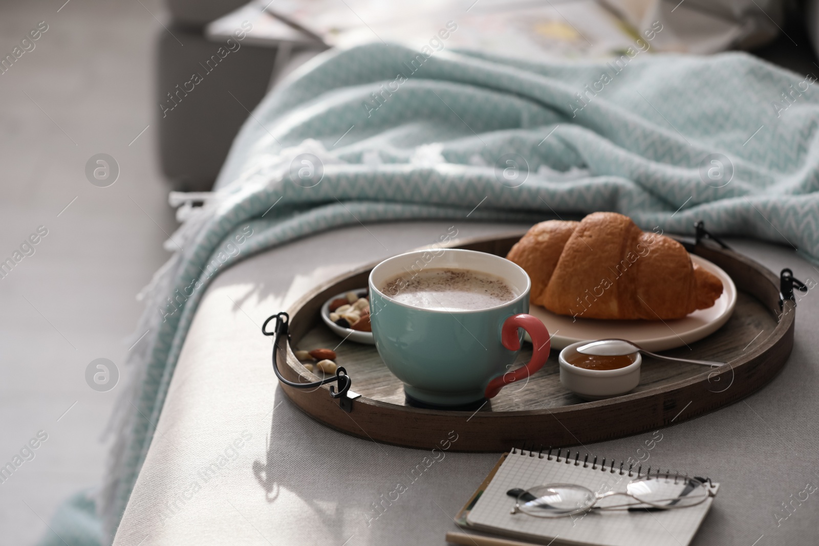 Photo of Tray with tasty breakfast on grey sofa in morning.  Space for text