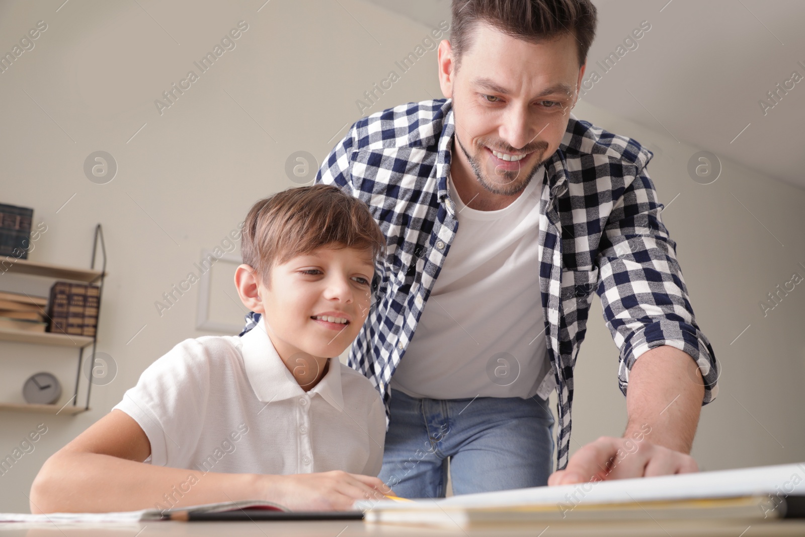 Photo of Dad helping his son with school assignment at home