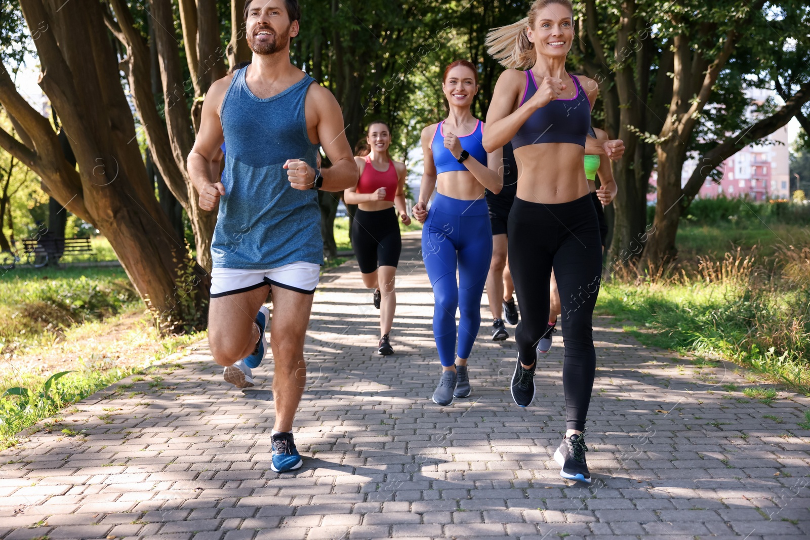 Photo of Group of people running in park on sunny day