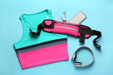 Photo of Flat lay composition with stylish pink waist bag on light blue background