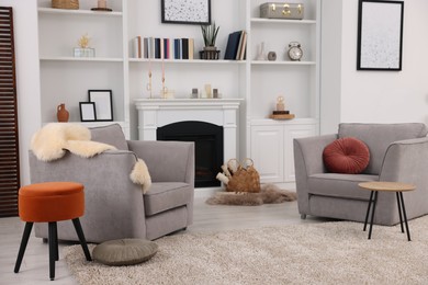 Photo of Comfortable armchairs, fireplace and shelves in living room. Interior design