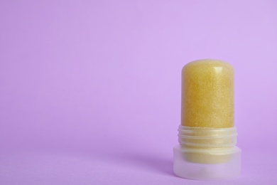 Photo of Natural crystal alum stick deodorant on lilac background. Space for text