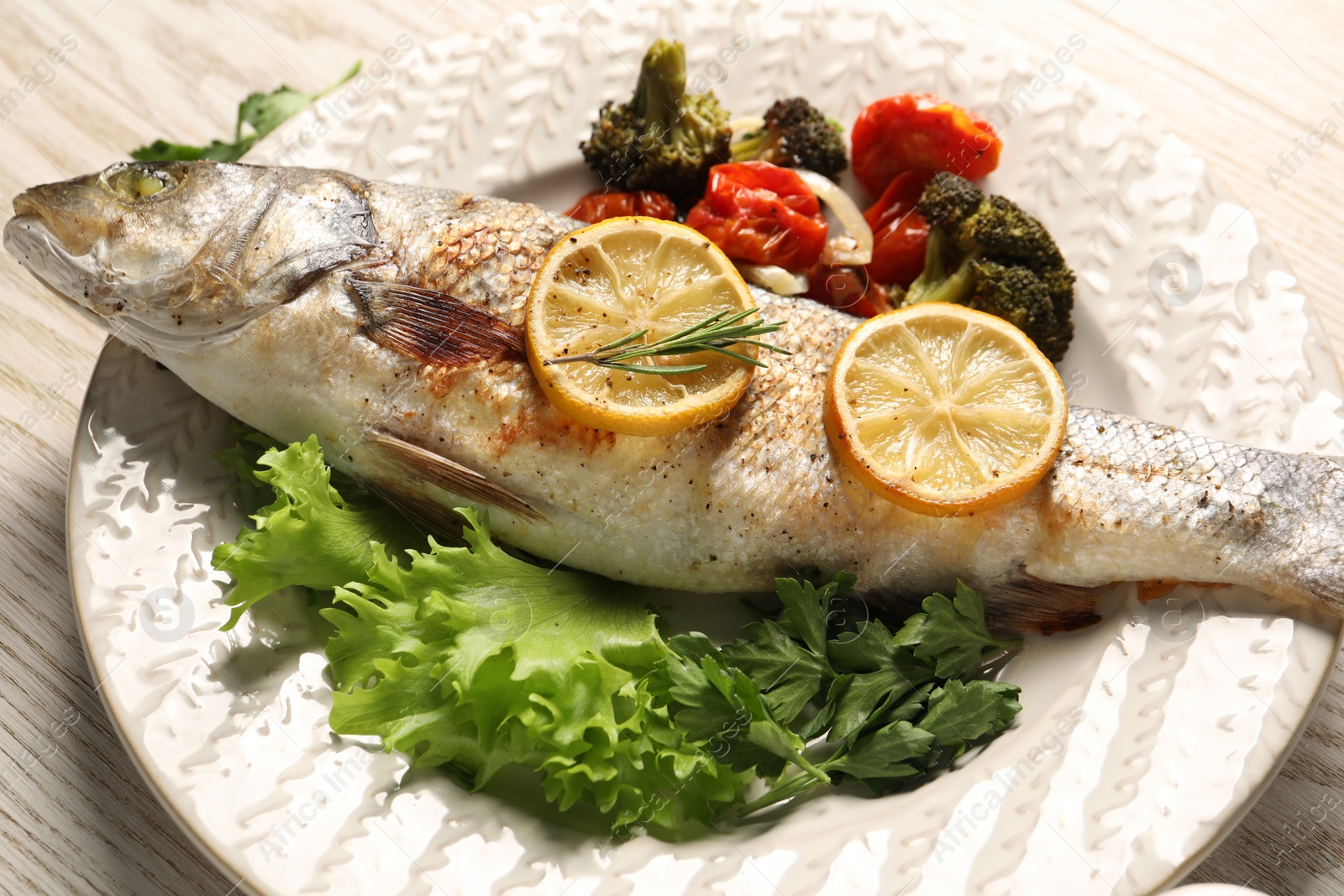 Photo of Delicious baked fish and vegetables on wooden table