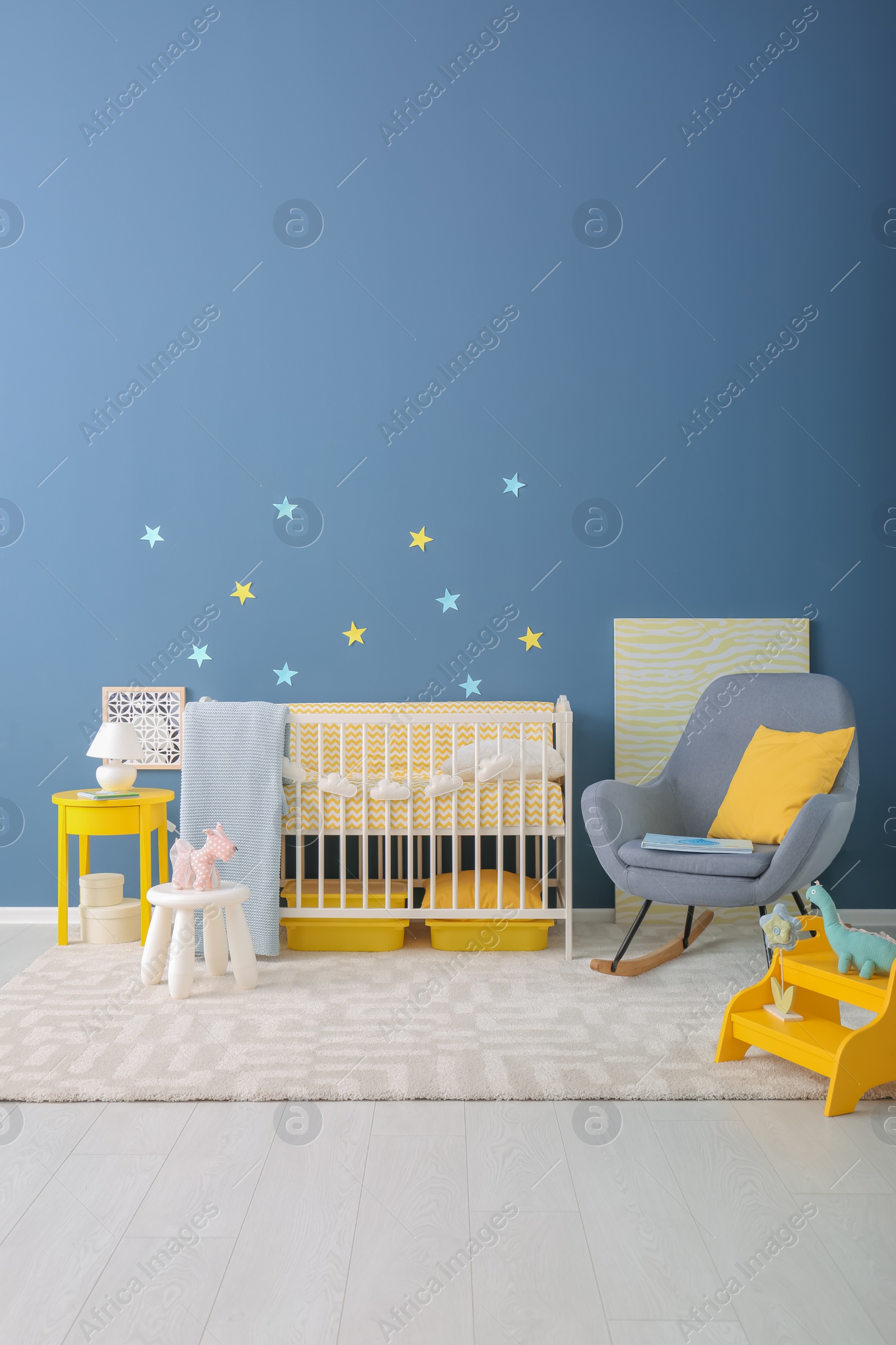 Photo of Baby room interior with crib and rocking chair near wall