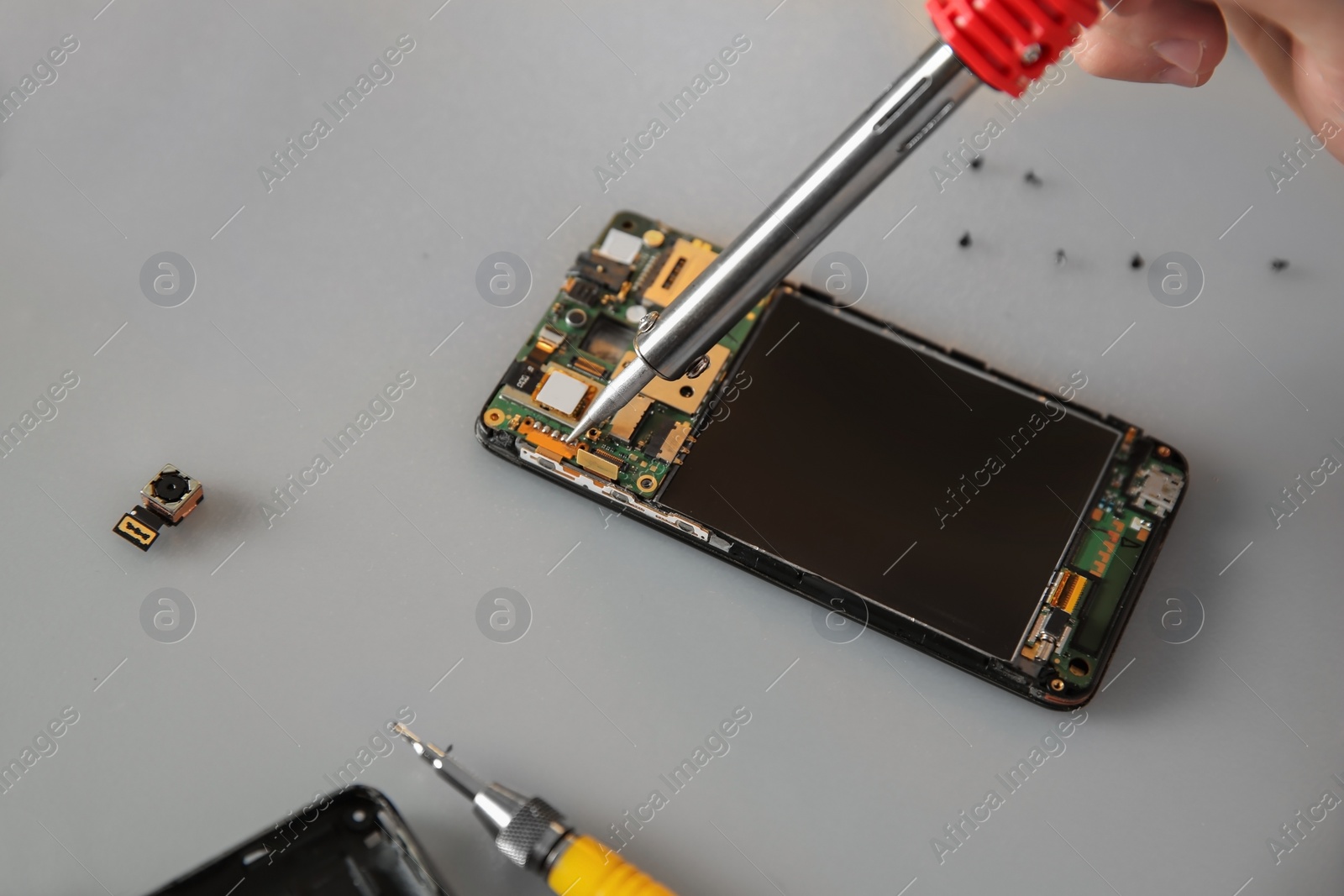 Photo of Technician repairing mobile phone at table, closeup