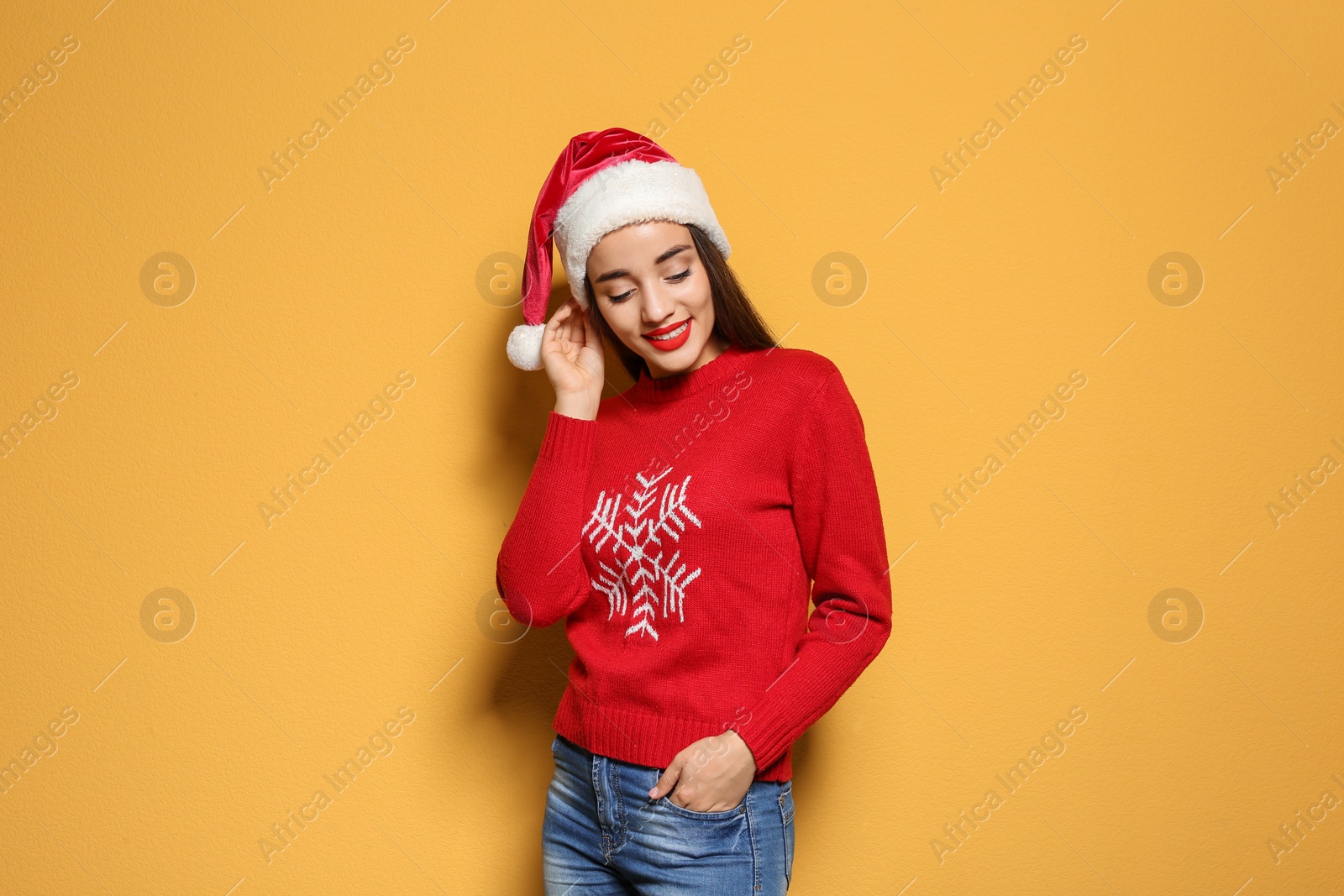 Photo of Young woman in Christmas sweater and hat on color background