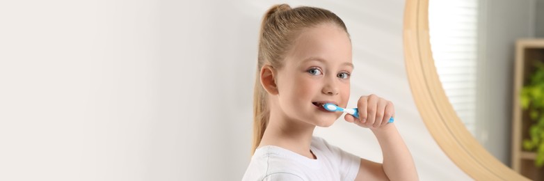 Image of Cute little girl brushing her teeth with plastic toothbrush in bathroom. Banner design with space for text