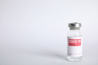 Vial with coronavirus vaccine on white background, space for text