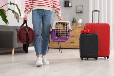 Photo of Travel with pet. Woman holding carrier with dog and bag at home, closeup