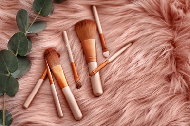 Flat lay composition with makeup brushes on faux fur