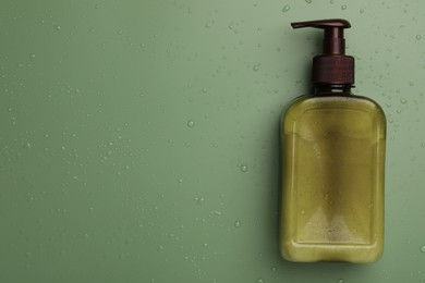 Bottle of face cleansing product on green background, top view. Space for text