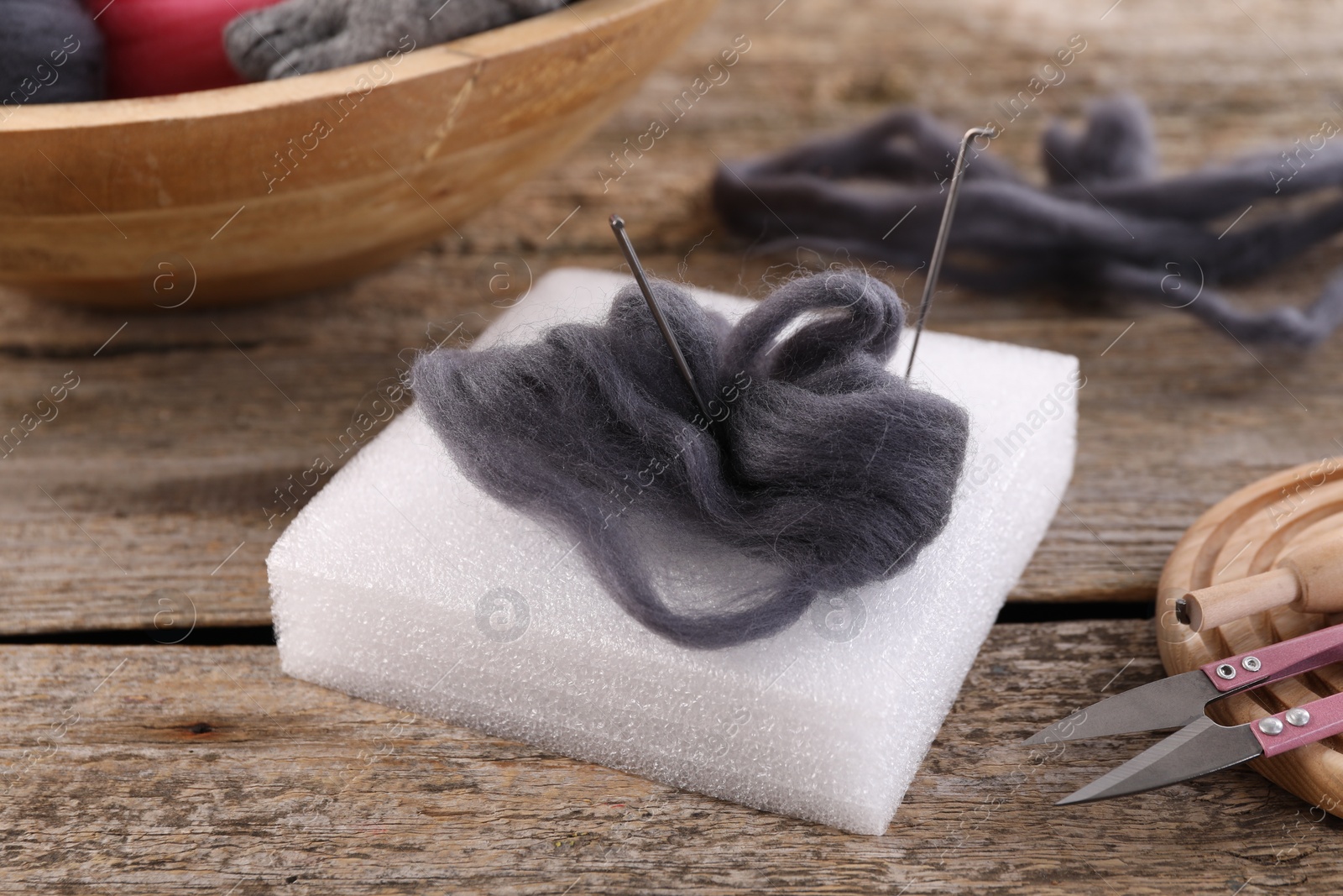 Photo of Felting tools and wool on wooden table, closeup