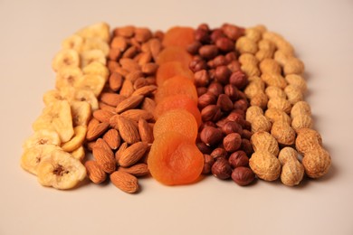 Photo of Mix of delicious dried nuts and fruits on beige background, closeup